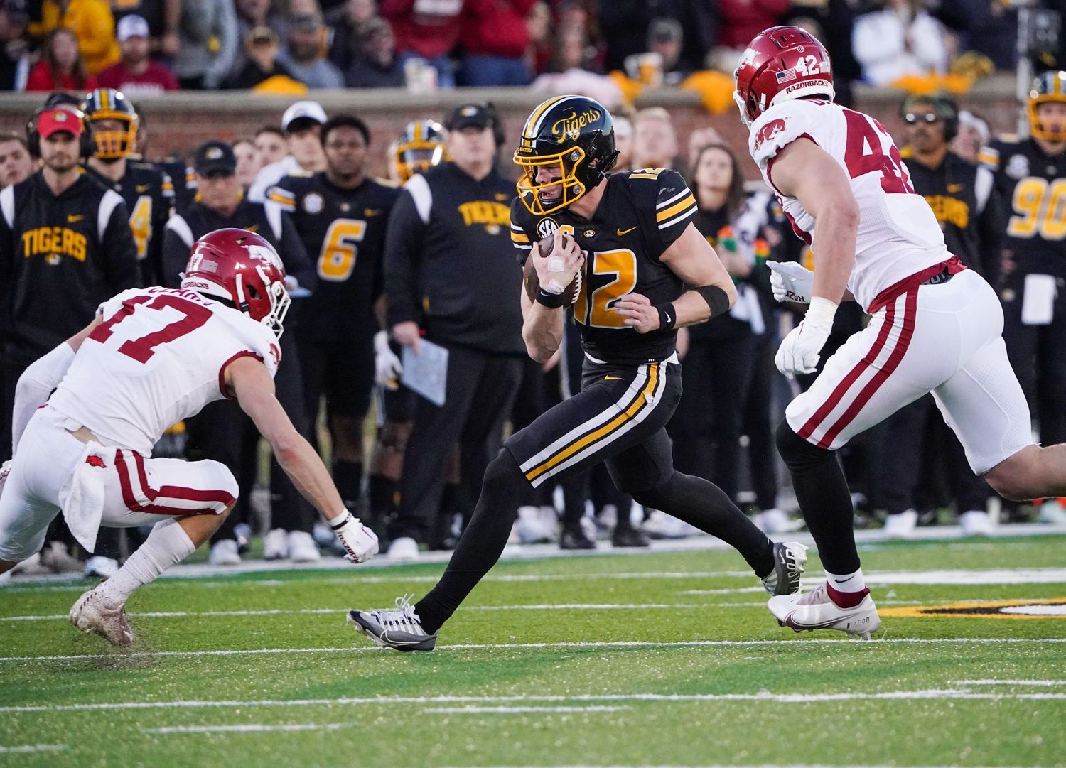 Nov 25, 2022; Columbia, Missouri, USA; Missouri Tigers quarterback Brady Cook (12) runs the ball as Arkansas Razorbacks defensive back Hudson Clark (17) and linebacker Drew Sanders (42) defend during the second half at Faurot Field at Memorial Stadium. Mandatory Credit: Denny Medley-USA TODAY Sports